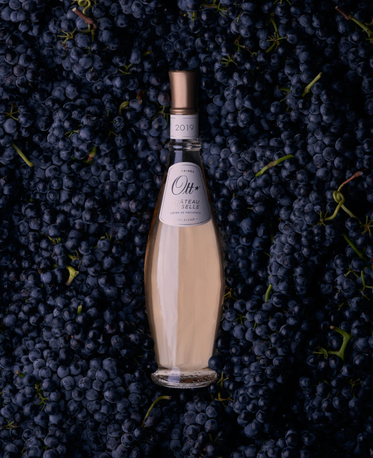 une-bouteille-de-chateau-de-selle-rose-plongee-au-milieu-de-raisins