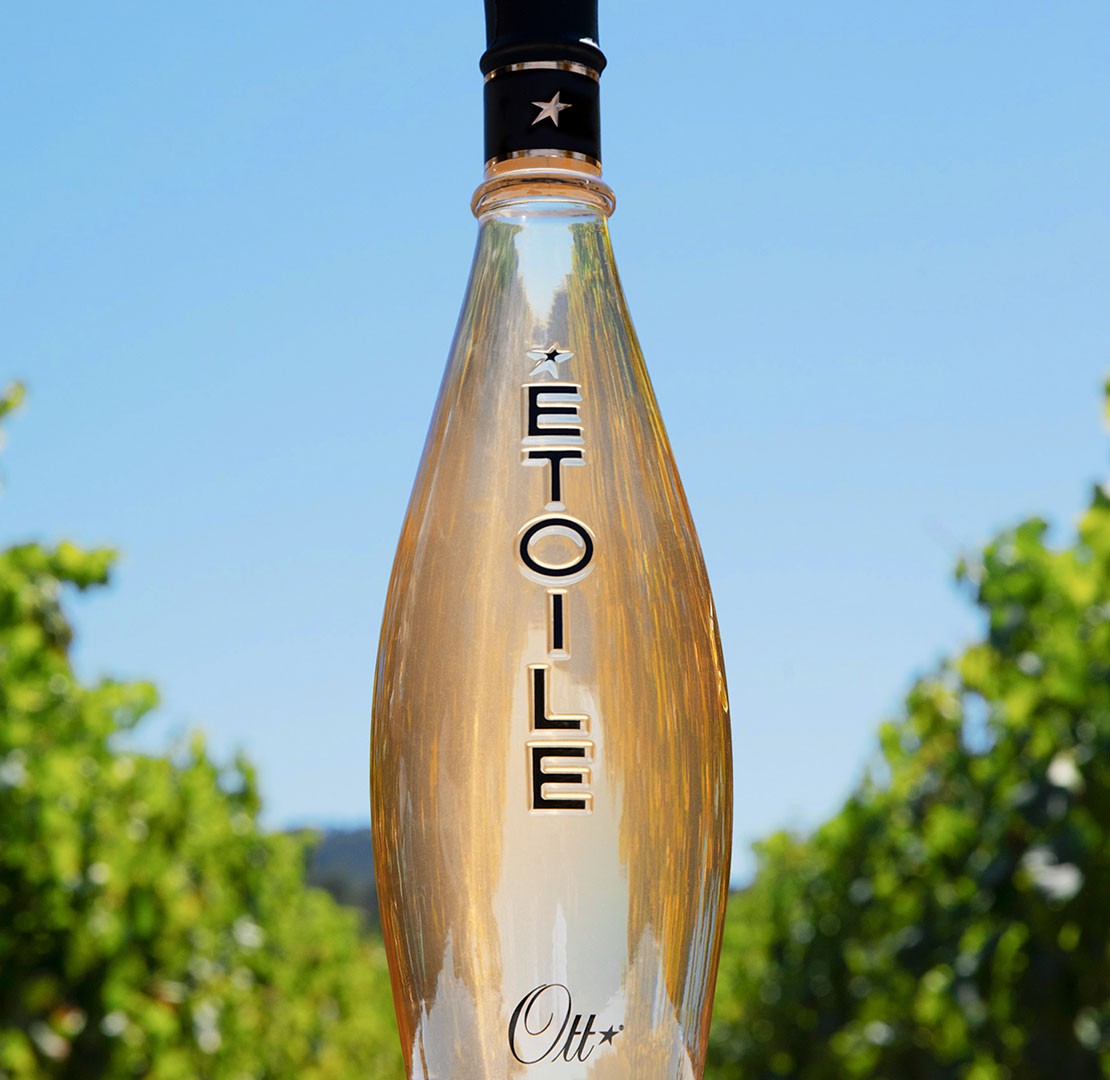 une-bouteille-de-vin-rose-etoile-au-milieu-de-deux-rangs-de-vignes-en-été